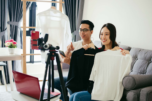 Two people film a live shopping video and showcase clothes as part of the emerging video commerce industry.