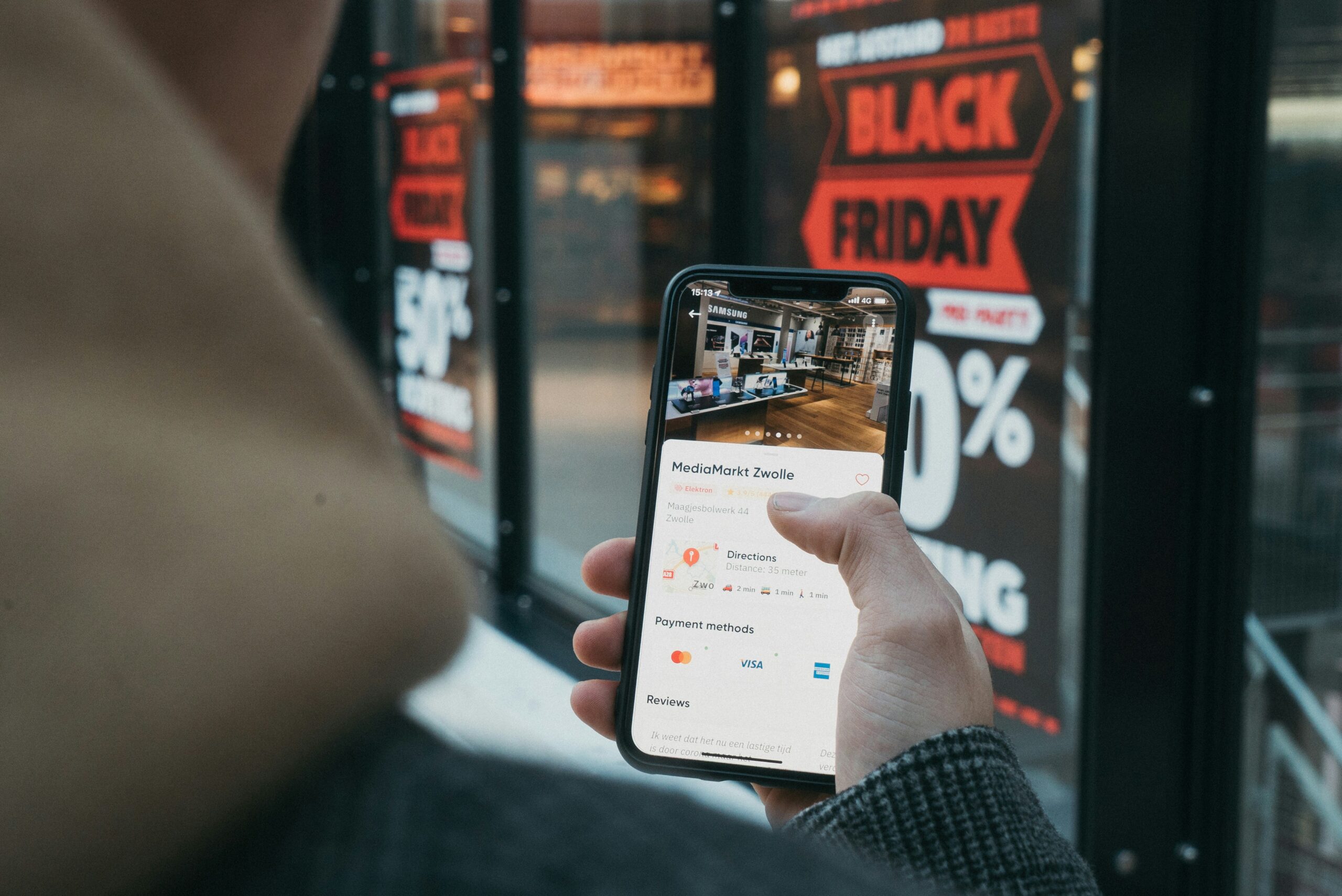 black-friday-ecommerce-strategy- man checking his phone as visiting a store on black friday