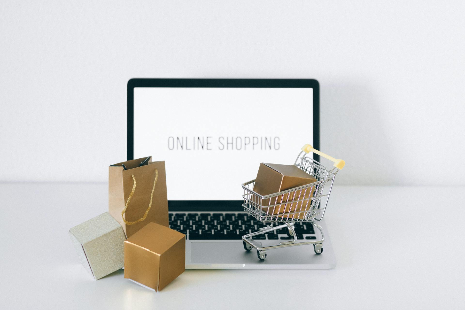 how-to-build-cosmetics-ecommerce-websites-laptop with shopping cart and shopping bags on the table